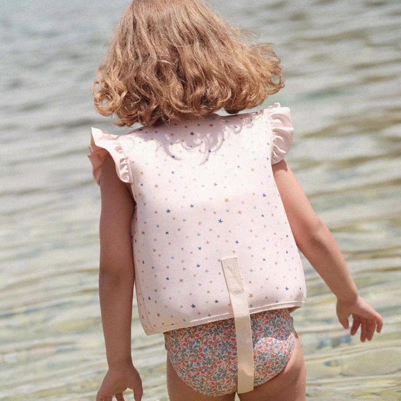 petite fille de dos qui porte un gilet de flottaison petit moussaillon a la mer
